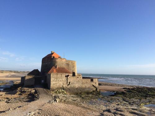 an old castle on a beach near the ocean at Hôtel Des Argousiers in Ambleteuse
