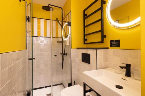 a bathroom with yellow walls and a sink and a shower at Hôtel Brady in Paris