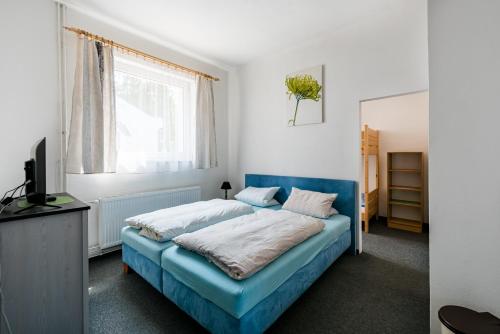 a bedroom with a blue bed and a window at penzion-sklarna in Dlouhá Ves