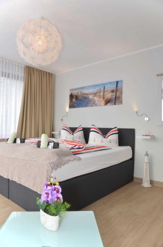 a bedroom with a large bed and a chandelier at Hotel Neptuns Ankerplatz in Cuxhaven
