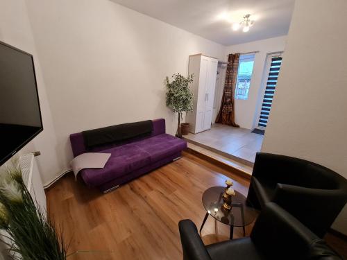 a living room with a purple couch and a table at Hotel Neptuns Ankerplatz in Cuxhaven