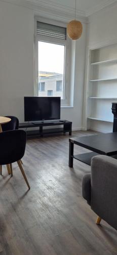 un salon avec une télévision, un canapé et une table dans l'établissement T3 09 Calme et Agréable Parking, à Roubaix