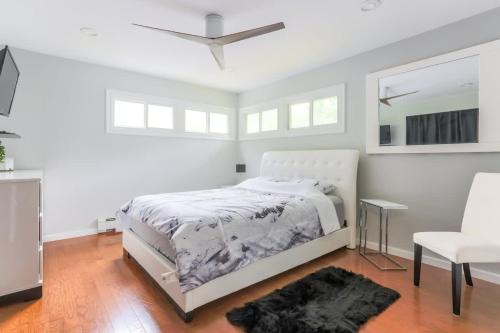 a white bedroom with a bed and a white chair at Relaxation Retreat Home with Hot Tub Gym & Sauna in Prattsville