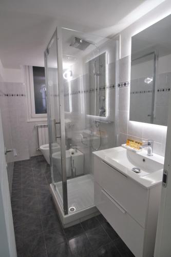 a white bathroom with a shower and a sink at Porto Antico Apartment in Genoa