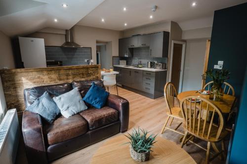 a living room with a leather couch and a kitchen at Swan House in Huddersfield