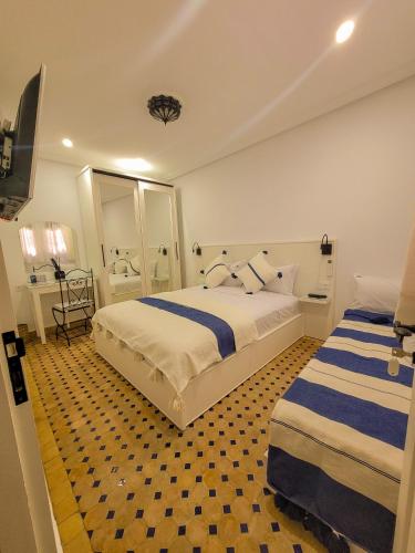 a hotel room with two beds and a bathroom at Dar Dahbia in Asilah