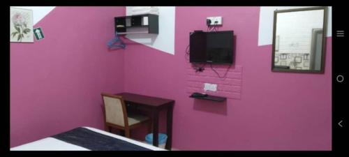 Habitación de color rosa con cama y TV en Langkawi Western Motel, en Pantai Cenang