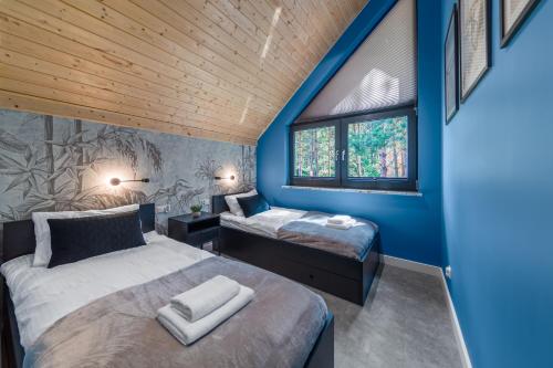 two beds in a room with blue walls at Sosnowy Szum Sauna 3 Wanny Spa in Jastrzębia Góra