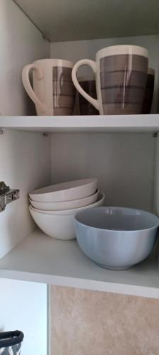 a white shelf with bowls and plates on it at NANA - Grand Appartement - C32- Cuisine équipée- CLIM-WIFI-Terrasse in Cayenne