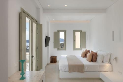 a white bedroom with a bed and two windows at ANEMOLETHE in Kimolos