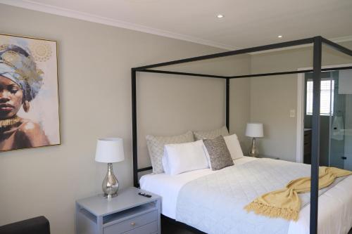 a bedroom with a large bed and a painting on the wall at High Hedges Guest Suites Constantia in Cape Town