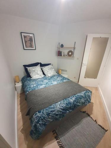 - une chambre avec un lit doté d'une couverture bleue et d'oreillers dans l'établissement Jardin de Thau, à Balaruc-les-Bains