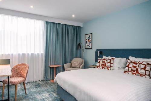 a hotel room with a bed and a chair at voco Winchester Hotel & Spa by IHG in Winchester