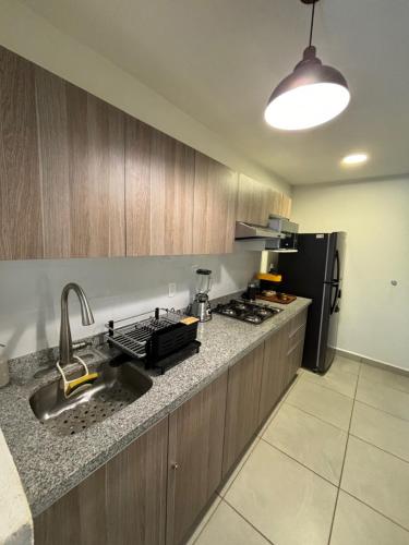 a kitchen with a sink and a black refrigerator at Departamento Boutique con más Amenidades que Ningún otro en la Zona in Acapulco