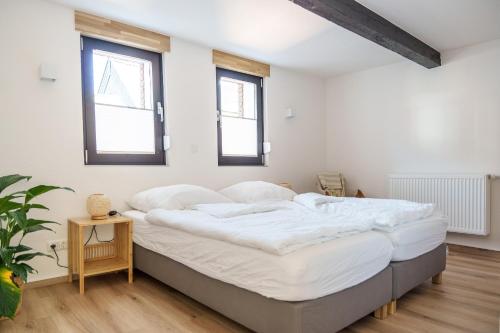 ein Schlafzimmer mit einem großen Bett mit weißer Bettwäsche in der Unterkunft Ferienhaus Ahorn, wunderschöne, neue Wohnungen, ideal für Ausflüge ins Phantasialand, die Städte Köln, Brühl und Bonn oder die Eifel in Weilerswist