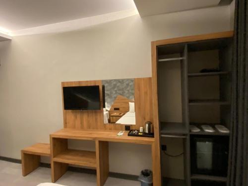 シャンルウルファにあるOtel OrtaDoğuのデスク、テレビ、棚が備わる客室です。