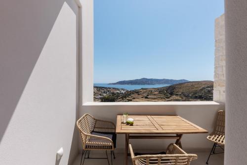 a table and chairs in a balcony with a view of the ocean at ANEMOLETHE in Kimolos