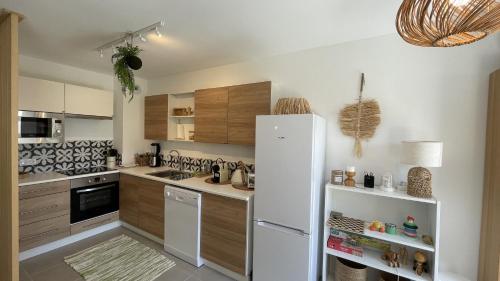 a kitchen with a white refrigerator and wooden cabinets at Le Clos Du Moulin 3, villa jardin, 3 chambres, près d'Avignon en Provence in Entraigues-sur-la-Sorgue