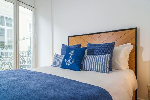 a bedroom with a bed with blue and white pillows at Varanda Azul - First Mate Loft (City Centre) in Ponta Delgada