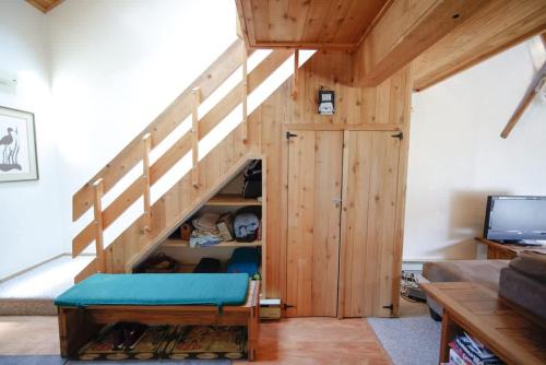 a living room with a wooden staircase with a blue bench at Windham Mountain Village Condo in Windham