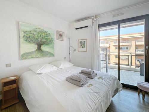une chambre avec un lit blanc avec des serviettes dessus dans l'établissement 50m2 Parking, Terrasse vue Mer, à Cannes