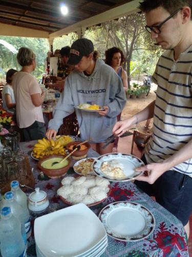 Eine Gruppe von Menschen steht um einen Tisch mit Essen. in der Unterkunft Udesh Guest in Polonnaruwa