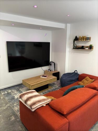 a living room with a couch and a flat screen tv at Les Alizées de Canet calme et moderne in Canet-en-Roussillon