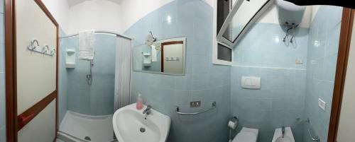 Un baño con azulejos azules, inodoro y lavabo. en La Casa di LULÚ, en Bari