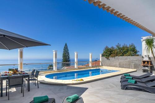a swimming pool in a patio with a table and chairs at Villa Atlantic Sunset by Villa Plus in Funchal