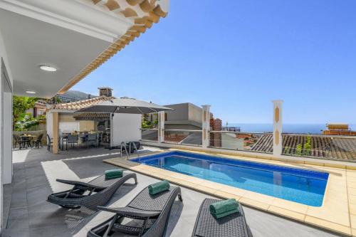 a swimming pool with chairs and an umbrella on a house at Villa Atlantic Sunrise by Villa Plus in Funchal