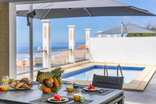a table with a bowl of fruit on it with a view of a pool at Villa Atlantic Sunrise by Villa Plus in Funchal
