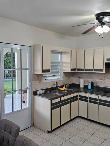 a kitchen with white cabinets and a ceiling fan at Casaplayuela in Camaceyes