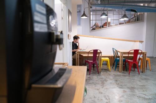 a man sitting at a table with a laptop at Koba Hostel in Donostia-San Sebastián