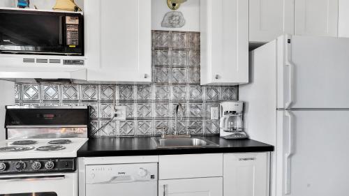 a white kitchen with a sink and a refrigerator at Montauk Oceanside Suites in Montauk