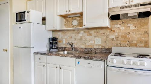 a white kitchen with a sink and a refrigerator at Montauk Oceanside Suites in Montauk