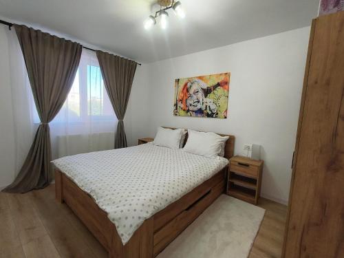 a bedroom with a bed and a painting on the wall at Apartament Theodora in Curtea de Argeş