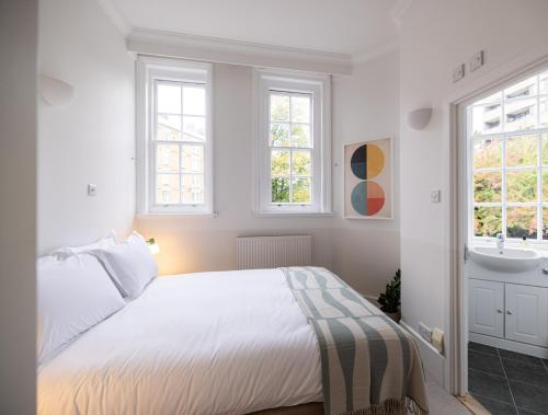 a white bedroom with a bed and a sink at The Regency by Nestor in London