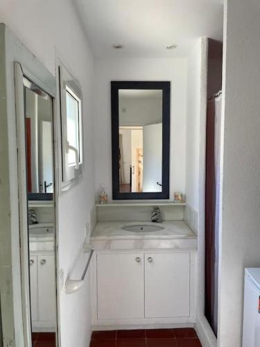 a white bathroom with a sink and a mirror at Casa pintora Neus in Cadaqués