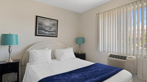 a bedroom with a bed with a blue blanket and a window at Montauk Oceanside Suites in Montauk
