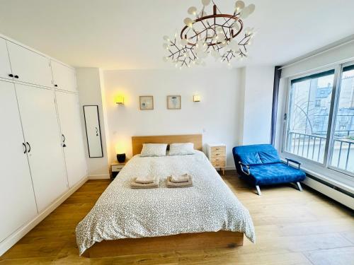 une chambre avec un grand lit et une chaise bleue dans l'établissement Dream Dwell Paris-Deluxe Studio 650m near Arc de Triomphe, à Paris