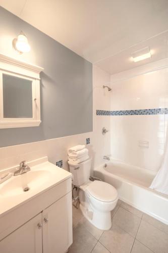 a bathroom with a white toilet and a tub and a sink at Montauk Oceanside Suites in Montauk