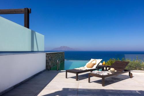 a balcony with two chairs and a table and a pool at Arpathea Villas in Foinikion