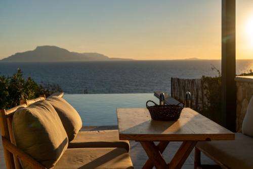 a bench and a table with a view of the ocean at Arpathea Villas in Foinikion