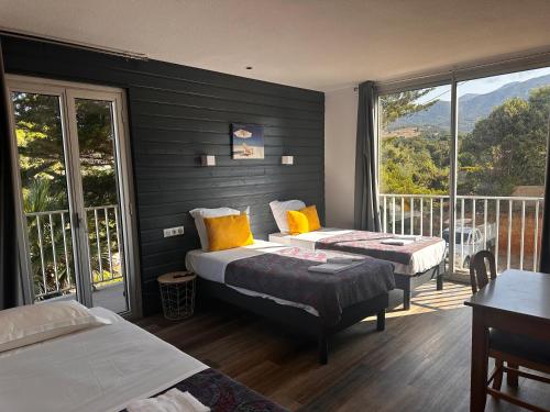 a hotel room with two beds and a balcony at Hôtel A RENA D'ORU in Coggia