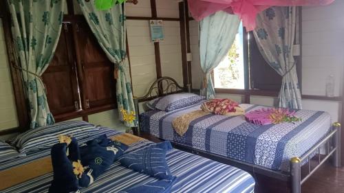 two twin beds in a room with a window at Baan Suan Kayoo 2 Buffalo Bay Aow Khao Kwai in Ko Phayam