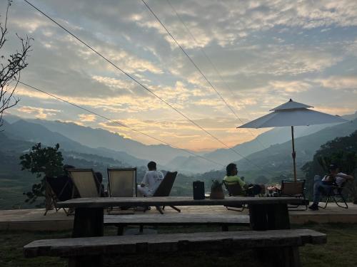 a group of people sitting at a table with an umbrella at Pavi garden in Sa Pa