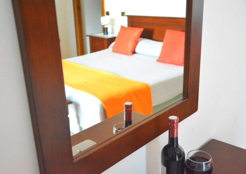 a mirror reflecting a bedroom with a bed and a bottle of wine at Agriturismo sul Sentiero in Pianillo