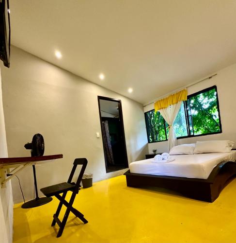 a bedroom with a bed and a desk and two windows at Amalaya Hostel in Restrepo