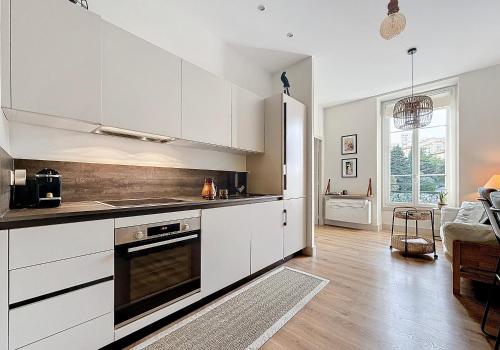 une cuisine avec des armoires blanches et un évier dans l'établissement Charming 2-Bedroom Retreat Near City Center with Excellent Transport Links, à Nice