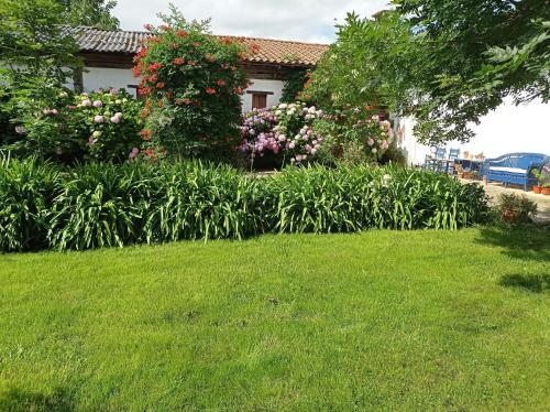 a yard with green grass and flowers and a house at Lokate 5 Habitaciones in Aia
